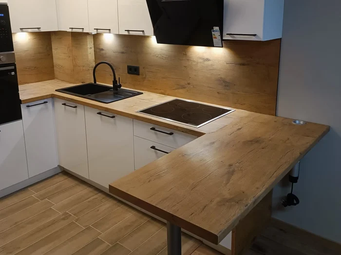 Weiße Küche mit Holzarbeitsplatte, schwarzer Spüle und Holztheke