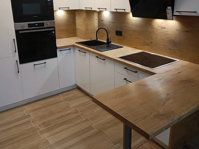 Weiße Küche mit Holzarbeitsplatte, schwarzer Spüle und Theke