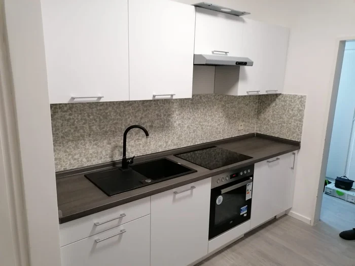 Weiße Küche mit Granitoptik-Arbeitsplatte, schwarzer Spüle und Backofen